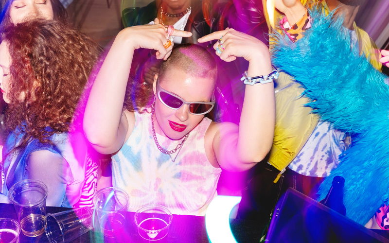 grupo bailando en una fiesta de los 2000 con estética Y2K y luces de neón