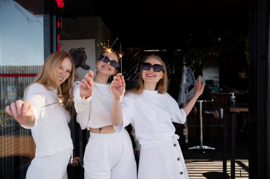 Amigas vestidas de blanco celebrando una fiesta blanca con bengalas