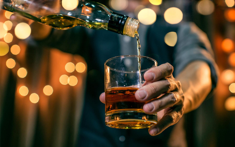 Barman sirviendo un cubata en barra mientras se aprecian los ingredientes