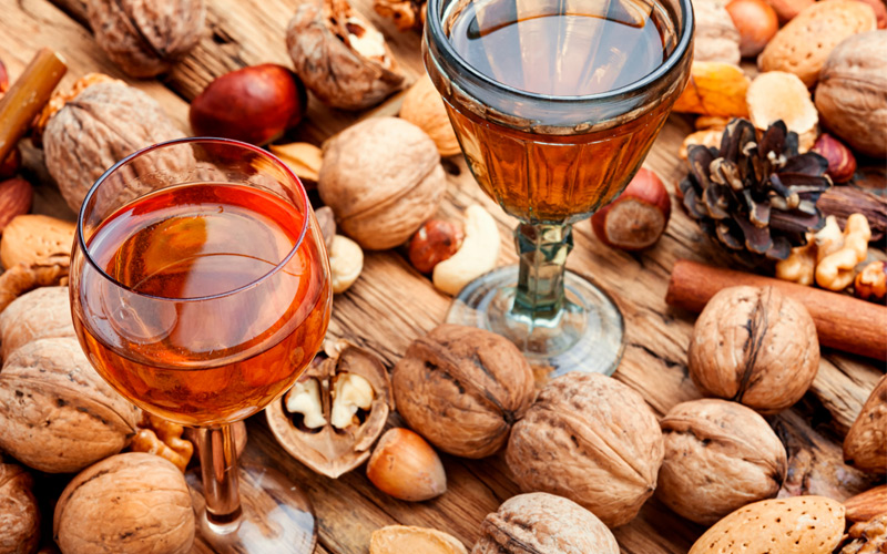 Dos copas de licor digestivo servidas entre nueces y otros frutos secos
